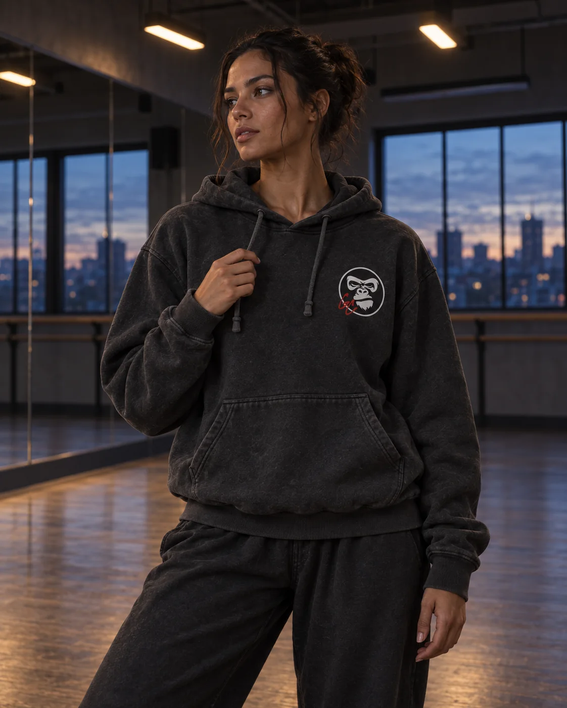 Illustrative campaign: an adult dancer in the charcoal GC Hoodie in a studio at dusk