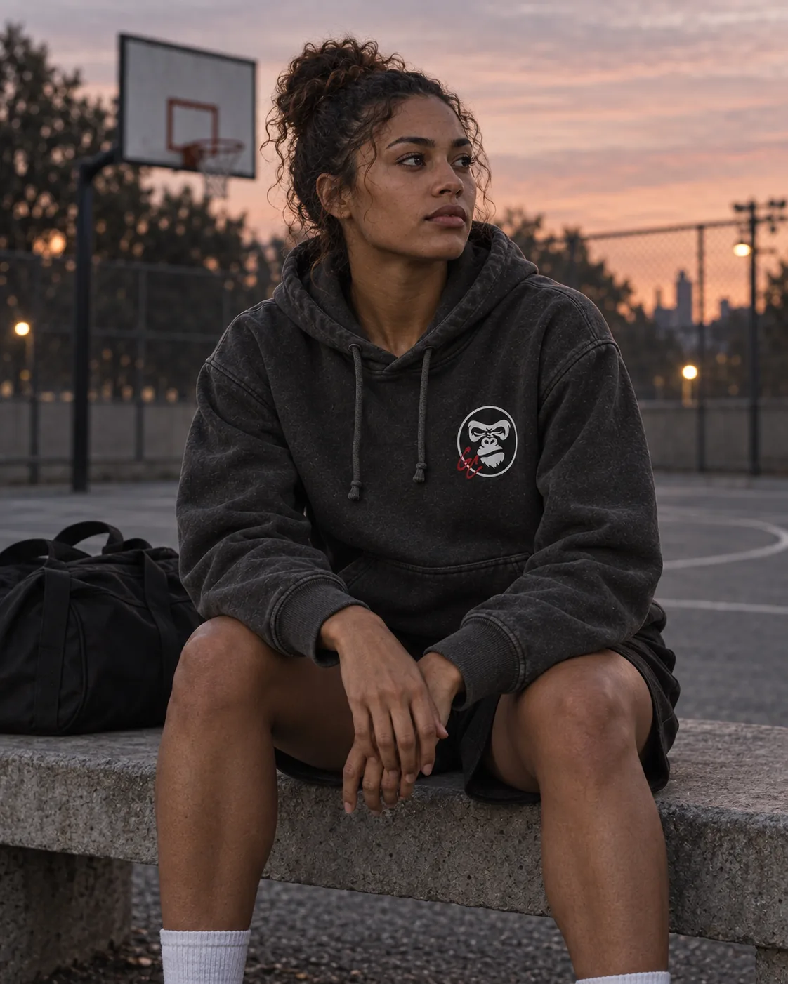 Illustrative campaign: an adult athlete in the GC Hoodie resting courtside at dawn